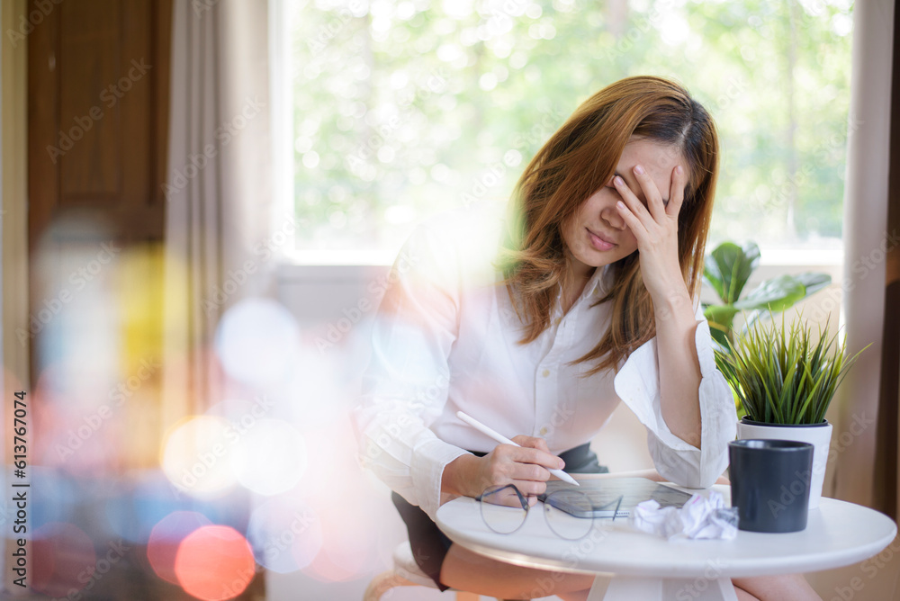 Young Asian woman feeling migraine head strain. Tired, Overworked businesswoman working on iPad at home Young Asian woman feeling migraine head strain. Tired, Overworked businesswoman working on iPad at home
