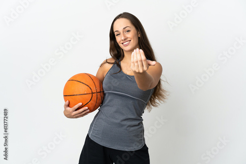 Young woman playing basketball over isolated white background inviting to come with hand. Happy that you came