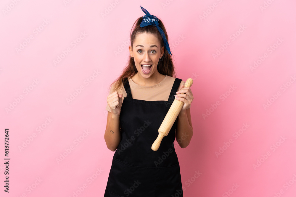 Young woman holding a rolling pin celebrating a victory in winner position Young woman holding a rolling pin celebrating a victory in winner position