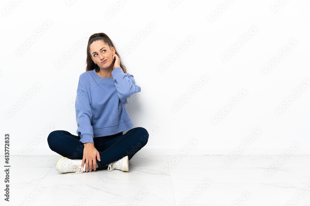 Young woman sitting on the floor having doubts