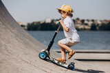 Cute little boy with curly hair riding scooter