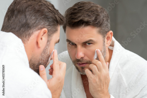 Matured man applying cosmetic cream on face. Facial treatment. Beauty portrait of man applying face cream. Skin care product. Moisturizing creme for wrinkle face skin. Perfect skin, morning routine.