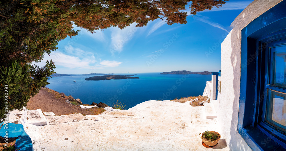 Panoramic image of white and blue chapel overlooking the caldera with blue sky of Santorini, Greece