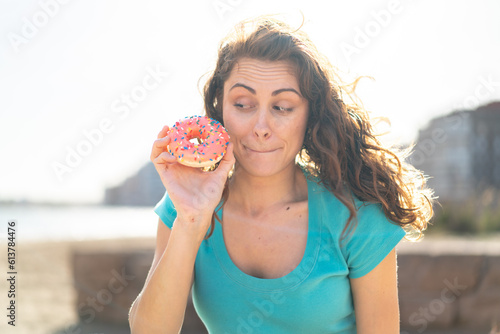 Young sport woman at outdoors holding a donut