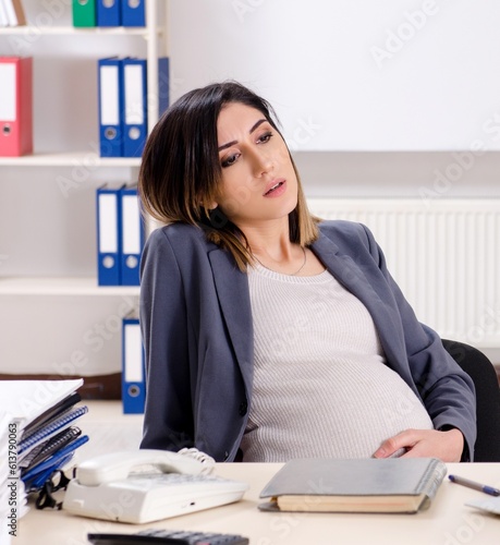 Young pregnant employee working in the office