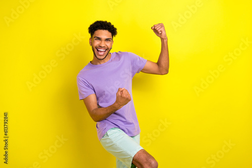 Photo of pretty lucky guy dressed purple t-shirt screaming rising fists isolated yellow color background