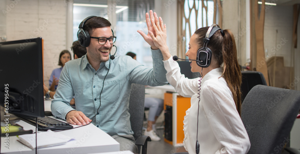 Cheerful customer support operators giving high-five to each other, celebrating a sale or success at work. Cheerful customer support operators giving high-five to each other, celebrating a sale or success at work.