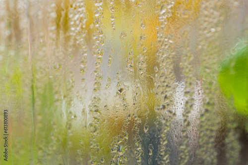 Raindrops on window glass on blur green background