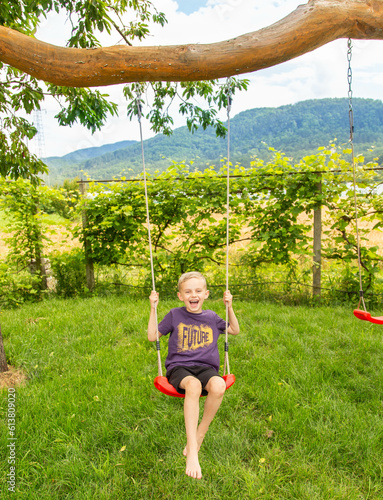 A boy of seven years old rides on a swing in the garden photo