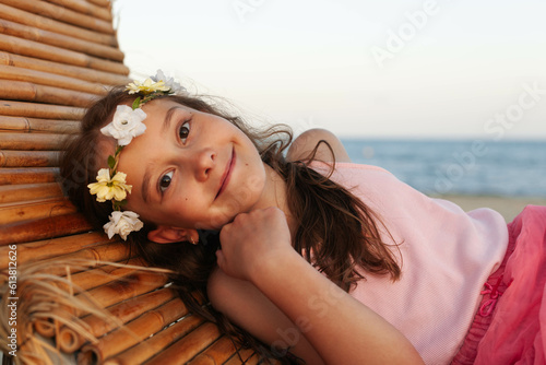 Portrait a beauteful caucasian little girls with pink dres on the Beach with Long Hair looking and wreath on her head looking ahead  at the sunset  photo