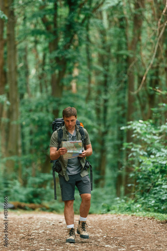 Walking forward with map in hands. Tourist in summer forest. Conception of exploration and leisure © standret