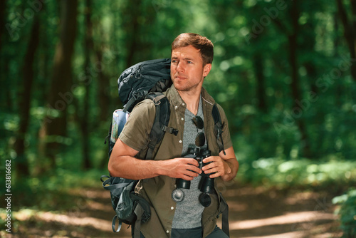 Navigation conception. With binoculars. Tourist in summer forest