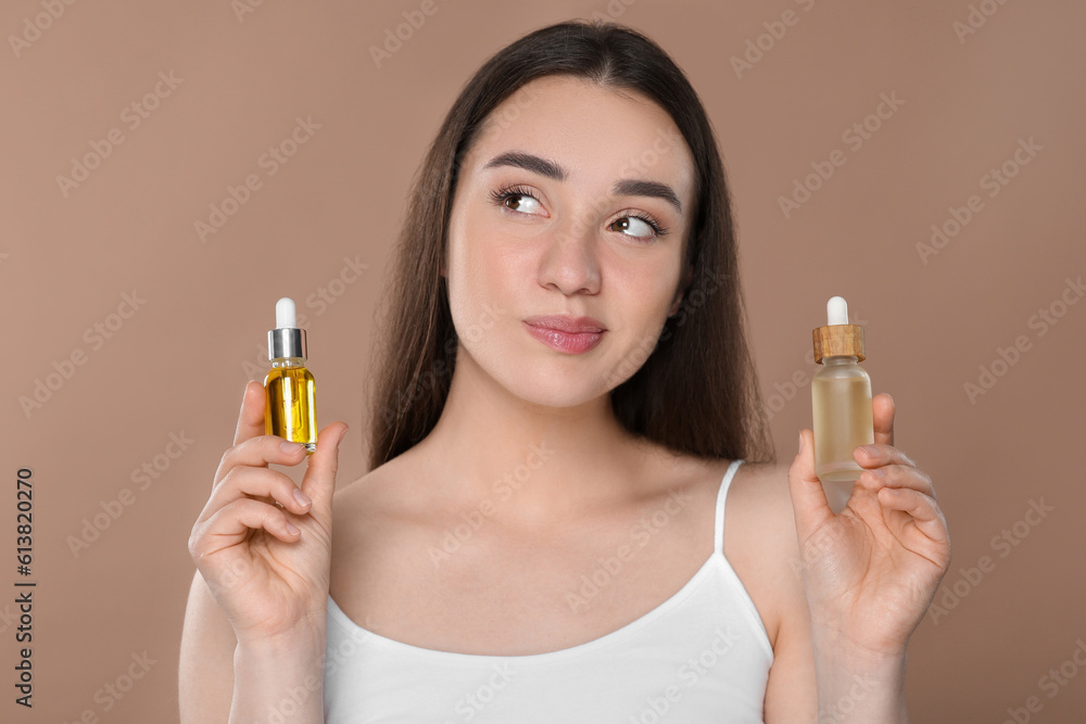 Fototapeta premium Woman with bottles of essential oil on brown background