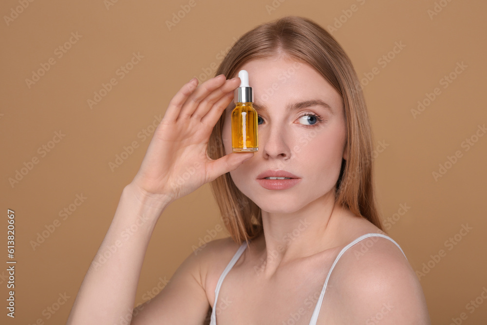 Beautiful young woman with bottle of essential oil on brown background Beautiful young woman with bottle of essential oil on brown background