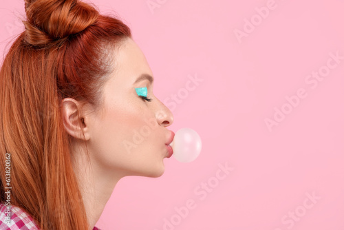 Beautiful woman with bright makeup blowing bubble gum on pink background. Space for text © New Africa