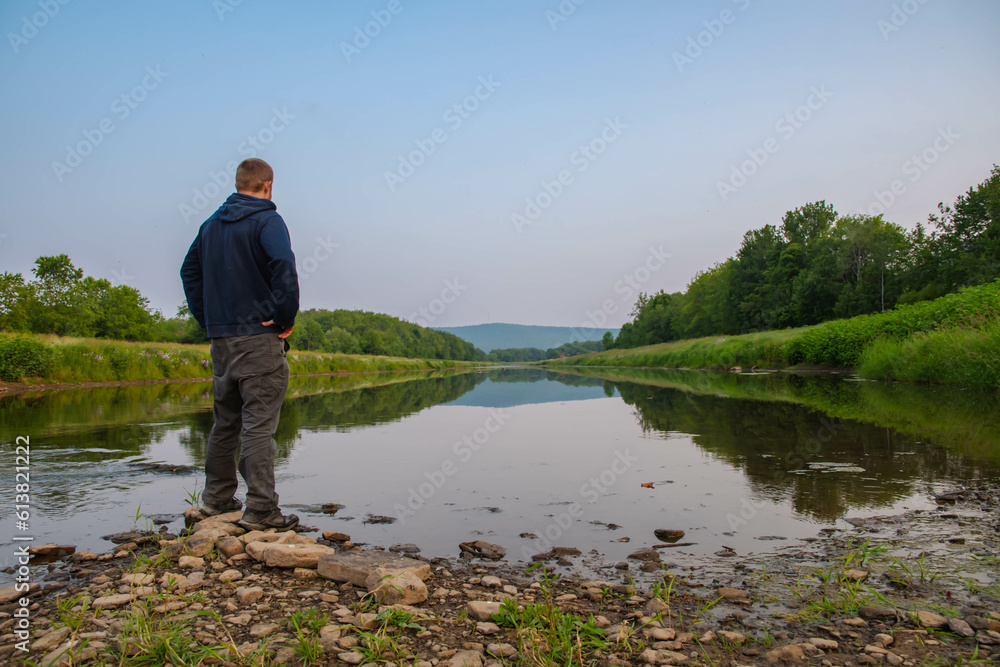 Man standing by the river summer activity hiker, cellphone talking in nature