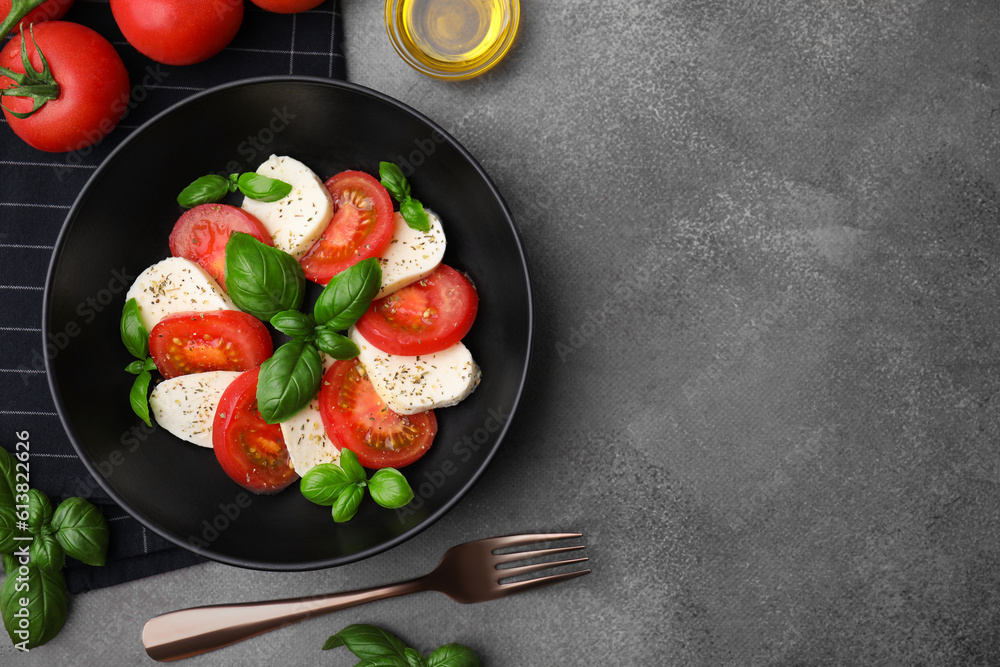 Delicious salad Caprese with tomatoes, mozzarella, basil and spices served on brown table, flat lay. Space for text