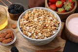 Tasty granola served with nuts and fresh berries on wooden board, closeup. Healthy breakfast