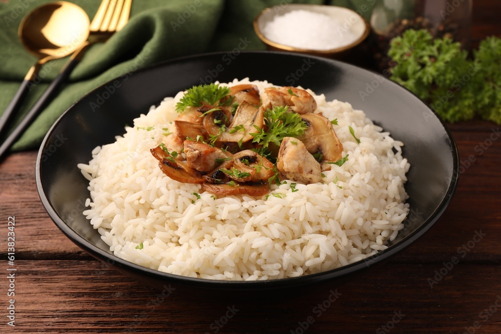 Delicious rice with mushrooms and parsley on wooden table, closeup Delicious rice with mushrooms and parsley on wooden table, closeup