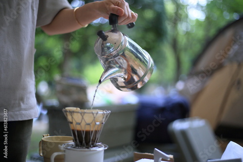 キャンプの朝食でドリップコーヒーを入れる女性