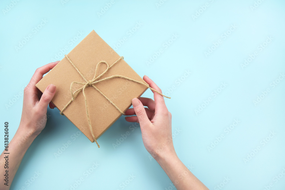 Female hands holding brown ecological package box made of natural corrugated cardboard. Female hands holding brown ecological package box made of natural corrugated cardboard.