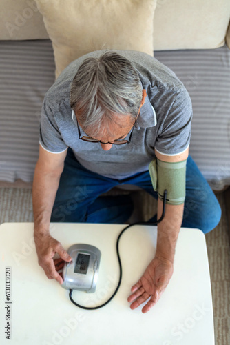 Close-up man measure pressure by yourself in room. Old man measures pressure at home.