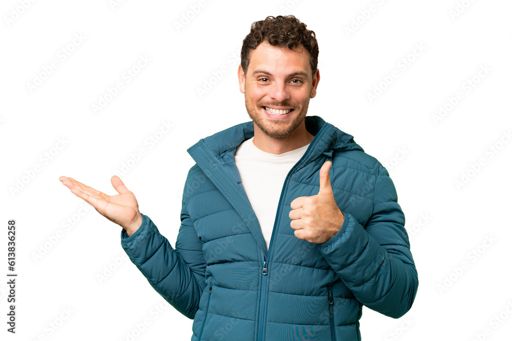 Brazilian man over isolated chroma key background holding copyspace imaginary on the palm to insert an ad and with thumbs up Brazilian man over isolated chroma key background holding copyspace imaginary on the palm to insert an ad and with thumbs up