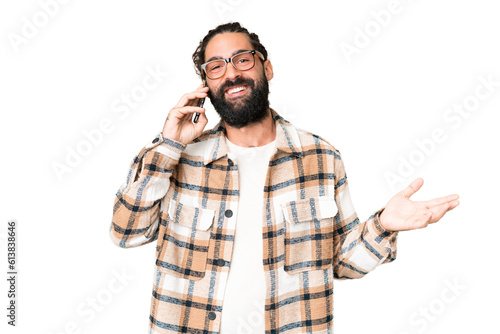 Young man with beard over isolated chroma key background keeping a conversation with the mobile phone with someone