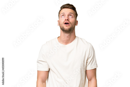 Young blonde caucasian man over isolated background looking up and with surprised expression