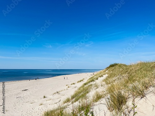 white sea dunes with some dry grass  clear blue sea
