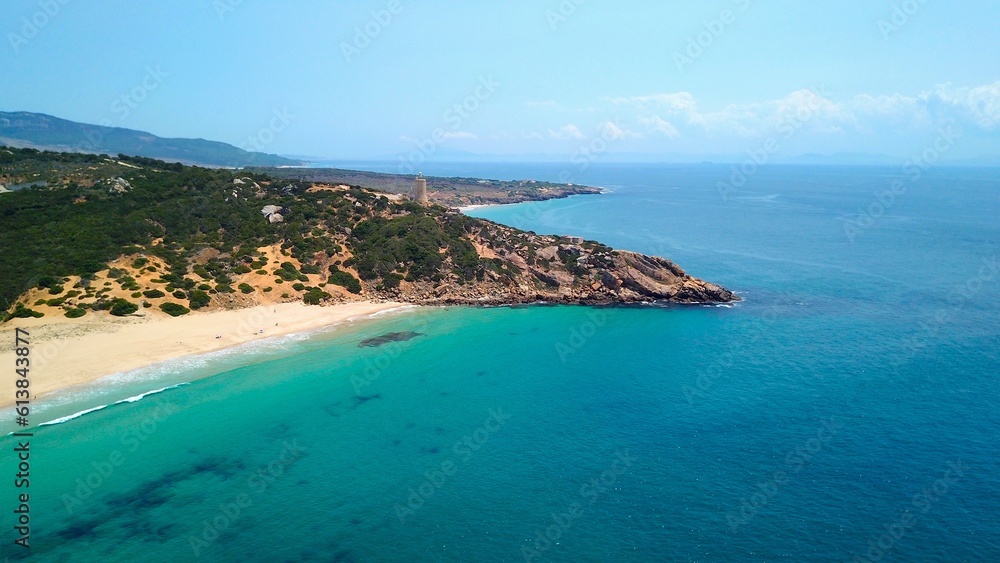 Faro de Camarinal, aerial view of the lighthouse on a cliff at the the wonderful sandy beach with the blue turquoise Atlantic Ocean, Playa Los Alemanes, Andalusia, Spain
