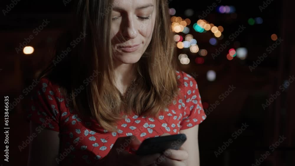 A woman uses a smartphone against the background of the evening city. Attractive woman chatting on the phone A woman uses a smartphone against the background of the evening city. Attractive woman chatting on the phone
