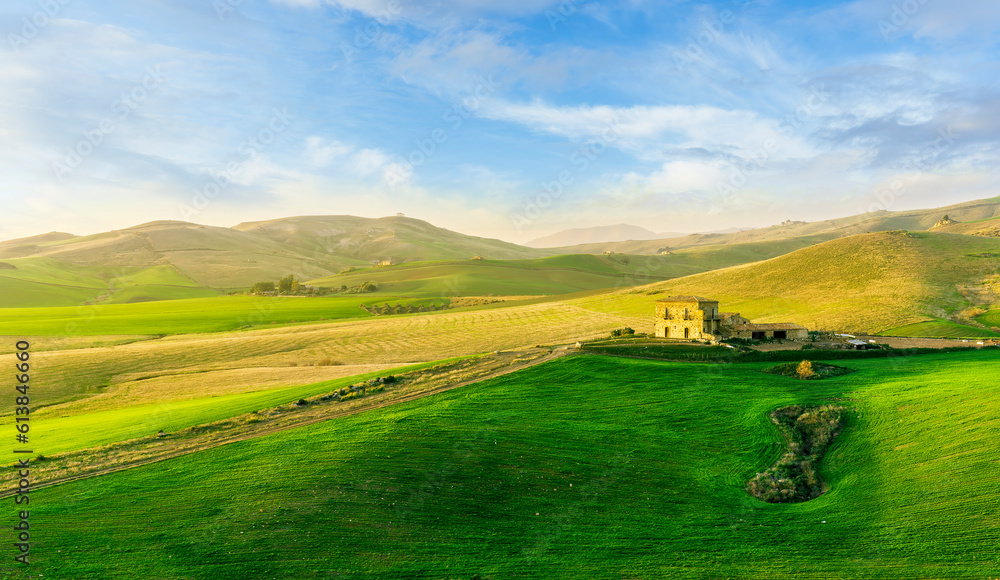 beautiful sunset or sunrise in rural countryside green hills with farm and mountains on background