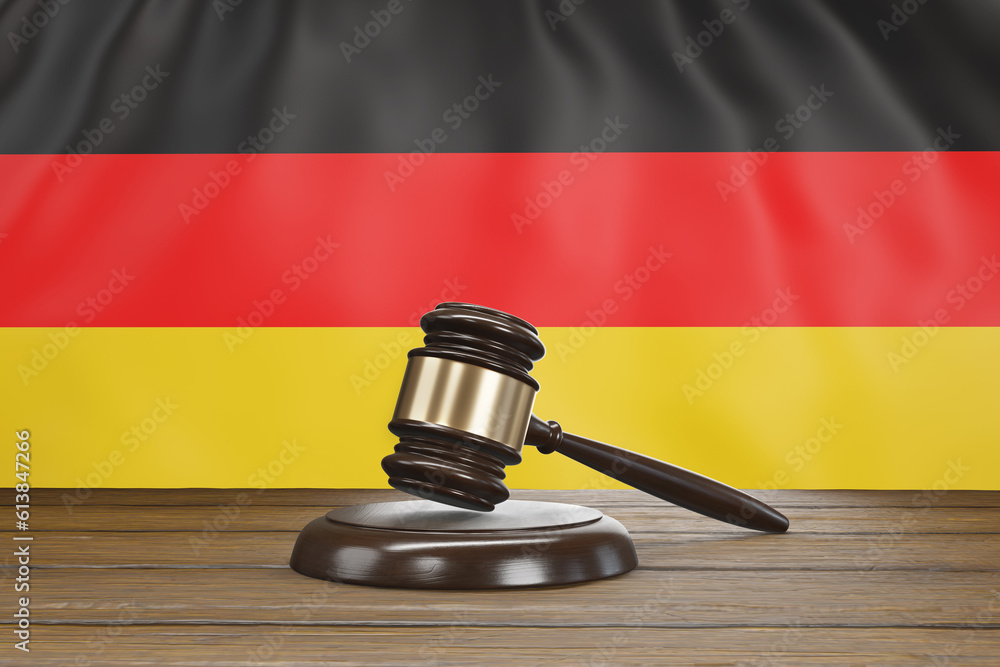 Small hammer gavel of judges of courts placed on a wooden table with the national flag of Germany as background. Illustration of the concept of German legal system and judicial issues
