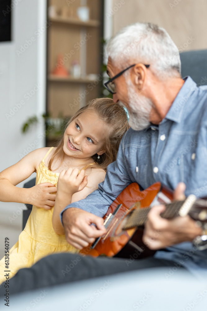 Little girl leans on her grandfather as he plays guitar Little girl leans on her grandfather as he plays guitar