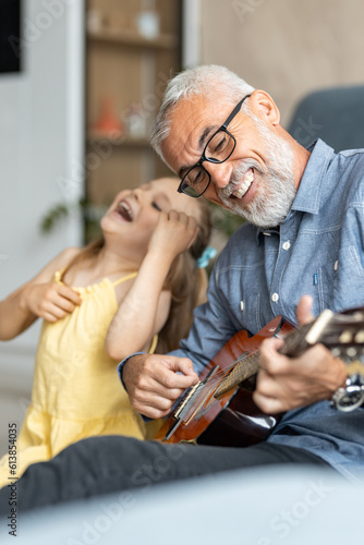 Grandfather laughing as his granddaughter pretends to play guitar with him