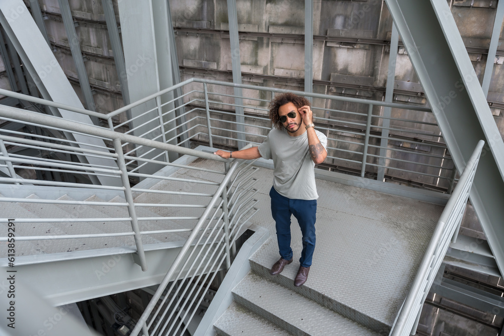 Young man with afro hair on the stairs in the city, cool urban fashion concept of a hipster guy with stylish
