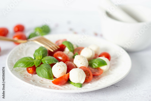 Italian caprese salad with sliced tomatoes, mozzarella, basil, olive oil on a light background.