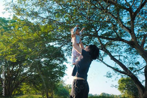 Happy mom lenjoying ift  up toddler boy in green park photo