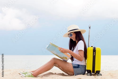 Summer Party. Traveler and tourism woman travel in summer on the beach and white sand. Asian is reading map with yellow suitcase. On working in vacation concept