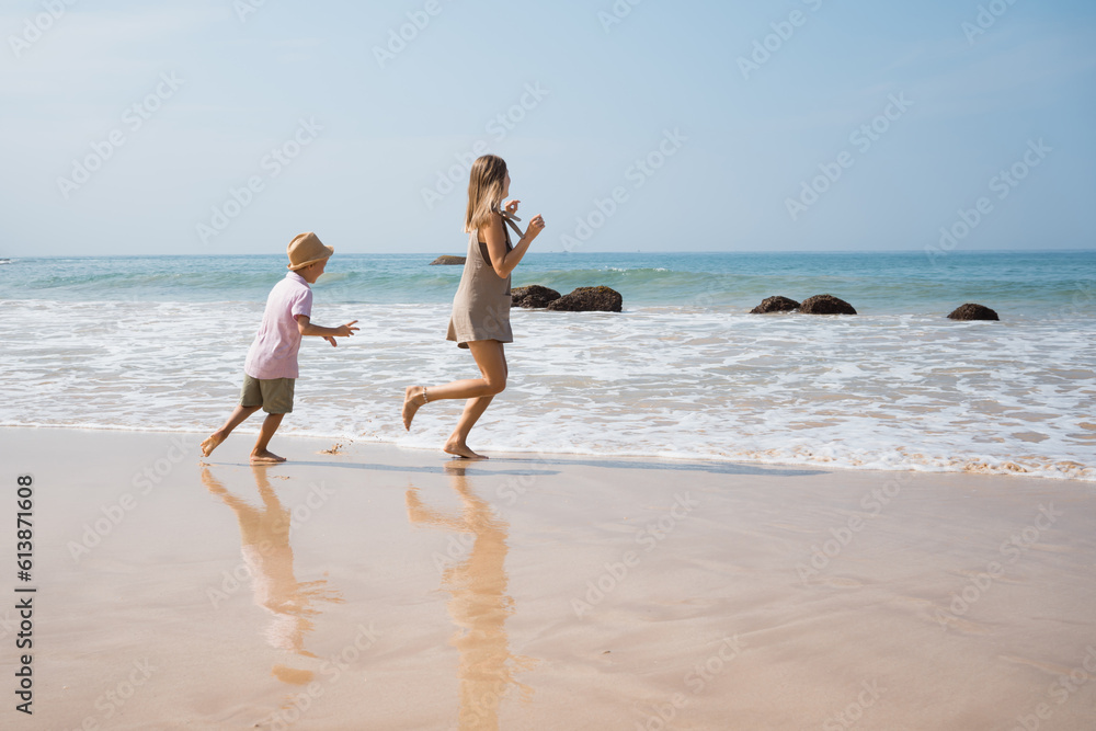 Beautiful young mother and son runing outside. beach vibes in sunny day