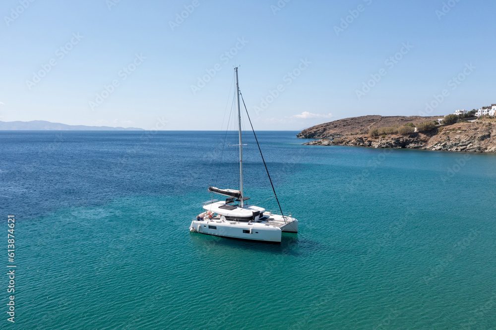 Sailing boat catamaran on rippled sea, rocky shore, summer vacation, Greek island Greece