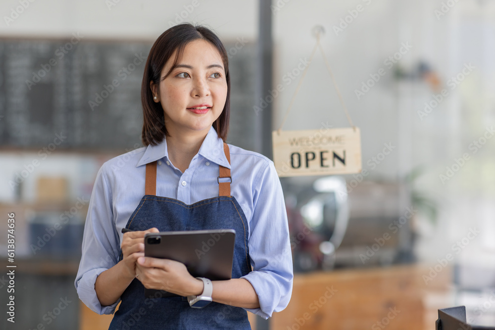 Fototapeta premium Startup successful small business owner sme beauty girl stand with tablet smartphone in coffee shop restaurant. Portrait of asian tan woman barista cafe owner. SME entrepreneur seller business concept