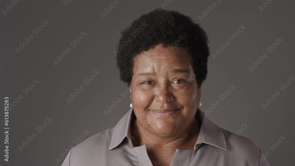 Chest up portrait of happy senior Black woman smiling at camera standing on graphite studio background Chest up portrait of happy senior Black woman smiling at camera standing on graphite studio background