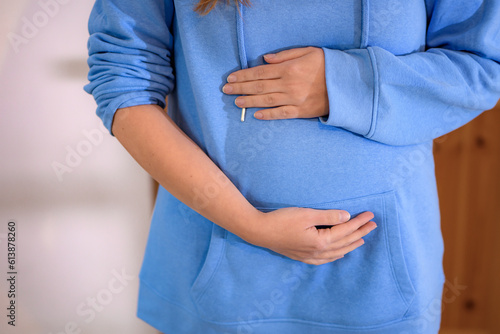 Młoda kobieta trzyma się za ciążowy brzuch. photo