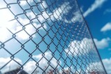 Metal chain link fence with a blue sky and clouds. Generative AI
