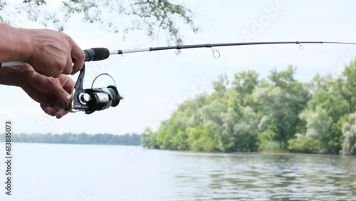 A man fishing from the shore on a fishing rod with a float and spinning, Lures for pike, solitude in the forest near the water.
 photo