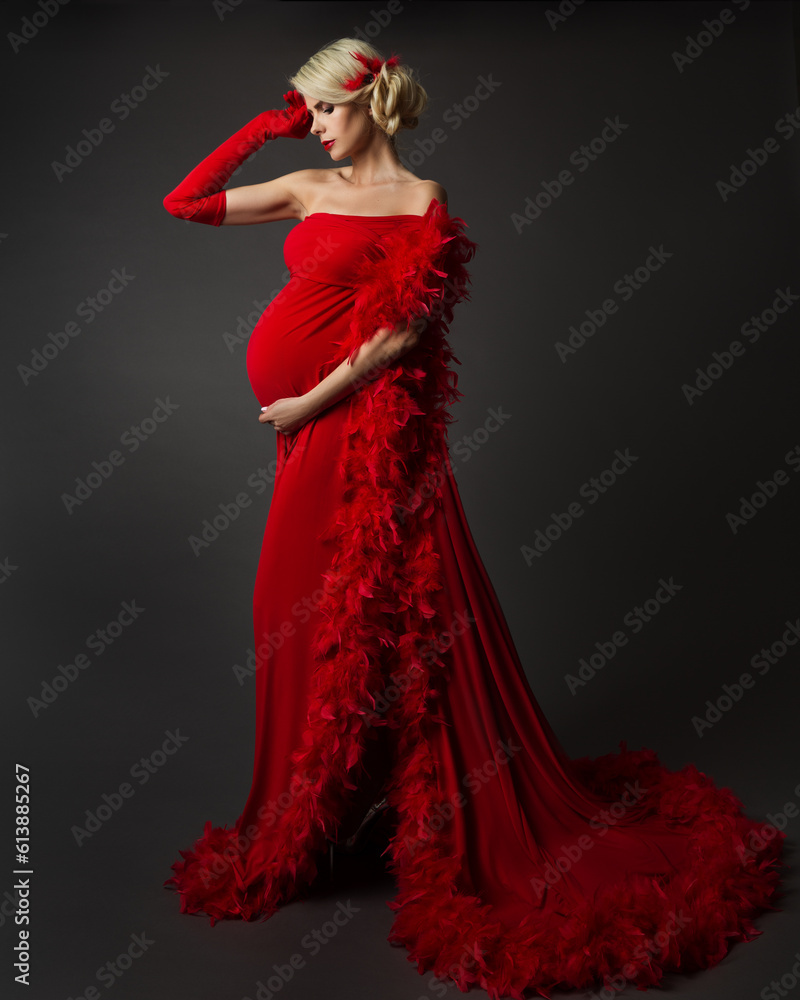 Fashion Pregnant Woman in Luxury Red Dress with Feather. Elegant Mother in evening Gown looking at Belly Side view. Pregnancy Stylish Clothes over Black Fashion Pregnant Woman in Luxury Red Dress with Feather. Elegant Mother in evening Gown looking at Belly Side view. Pregnancy Stylish Clothes over Black