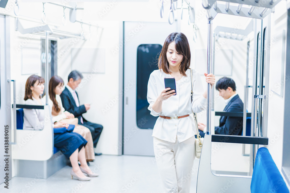 Obraz premium 電車でスマホを使う若い女性