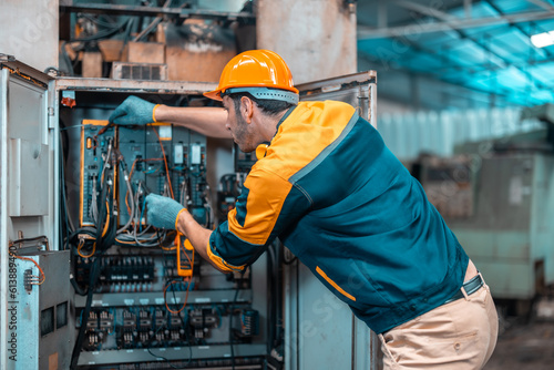 Electrical technician tests wiring, polarity, grounding, voltages and performs electrical maintenance using hand tools that involve clamp meter, screwdriver, and cutter. The foreman's routine tasks. photo